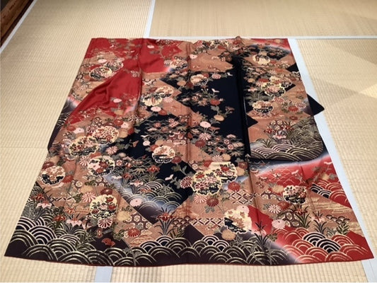 Furisode (long-sleeved kimono) in deep red, orange, dark brown, and black, featuring snowflakes, wave patterns, and seasonal flowers.